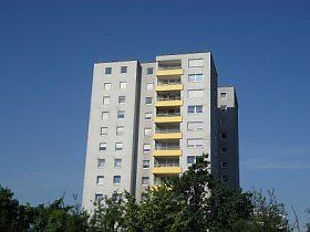 Ein hohes Gebäude mit gelben Balkonen vor einem blauen Himmel.