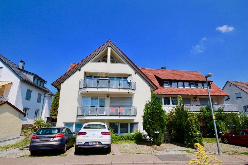 Zwei Autos parken vor einem großen weißen Gebäude.