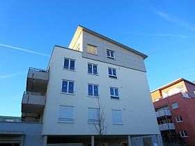 Ein großes weißes Wohnhaus mit einem blauen Himmel im Hintergrund.