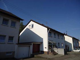 Ein weißes Haus mit einer Garage und einer Treppe davor.