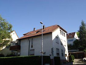 Ein weißes Haus mit einem roten Ziegeldach und einer Straßenlaterne davor.