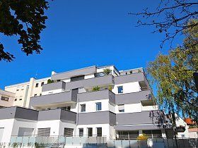 Ein großes Wohnhaus mit Balkonen und einem blauen Himmel im Hintergrund.