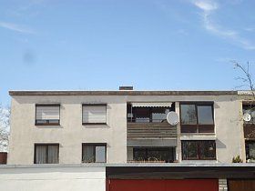 Ein großes weißes Gebäude mit vielen Fenstern und einem blauen Himmel im Hintergrund.