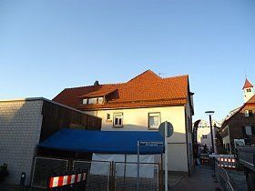 Ein weißes Gebäude mit einem roten Dach und einer blauen Markise an der Seite.