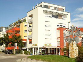 Ein großes Gebäude mit vielen Fenstern und einer Statue davor.