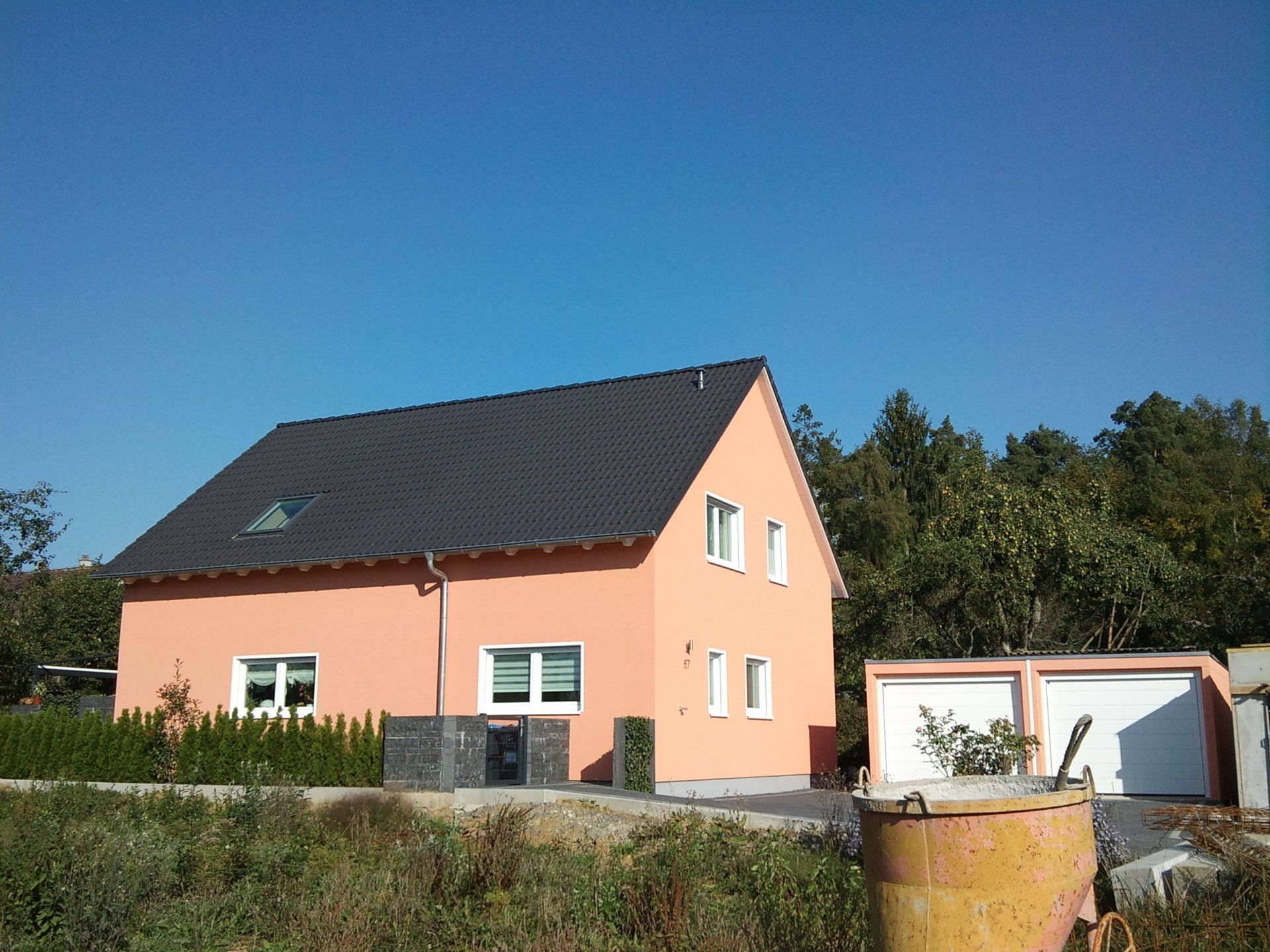 Ein Haus mit einer Garage und einem Eimer davor