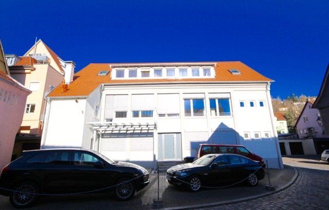 Autos parken vor einem weißen Gebäude mit rotem Dach