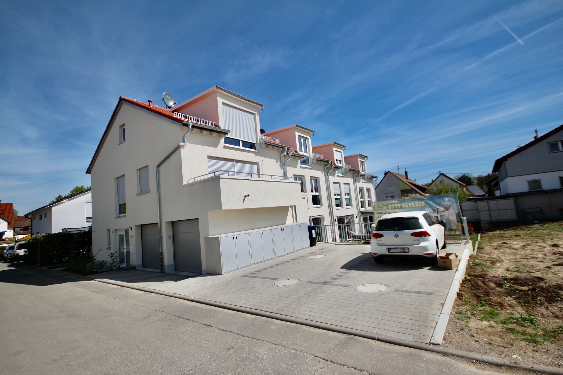 Ein weißes Auto parkt vor einem weißen Gebäude.