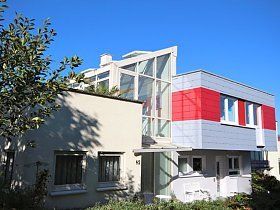 Ein rot-weißes Haus mit vielen Fenstern und einem Baum davor.