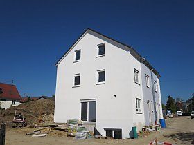 Inmitten eines Feldes wird ein weißes Haus gebaut.