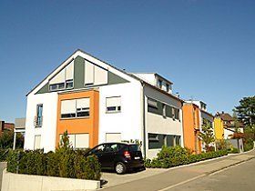 Vor einem großen Gebäude ist ein Auto geparkt.