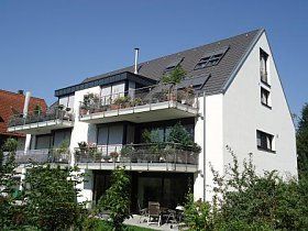 Ein großes weißes Haus mit Balkonen und einem blauen Himmel im Hintergrund.