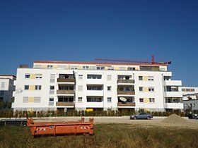 Ein großes weißes Gebäude mit einem davor geparkten Auto.