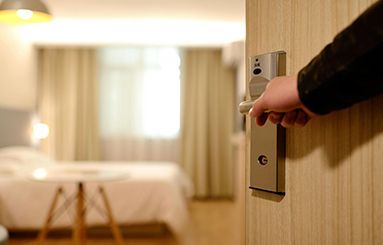 A person is opening a door in a hotel room.