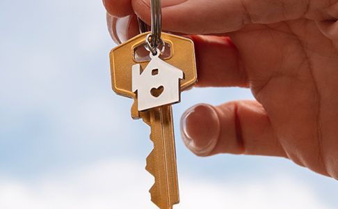 A person is holding a key with a house on it.