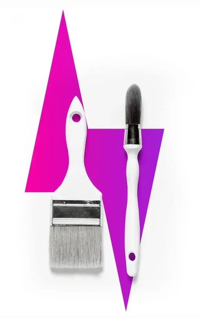 Two paint brushes, white handles, positioned over a pink and purple geometric shape, white background.
