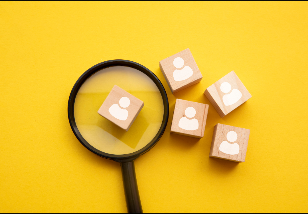 Person using a smartphone with email icons overlaying, near an open laptop in a cafe.