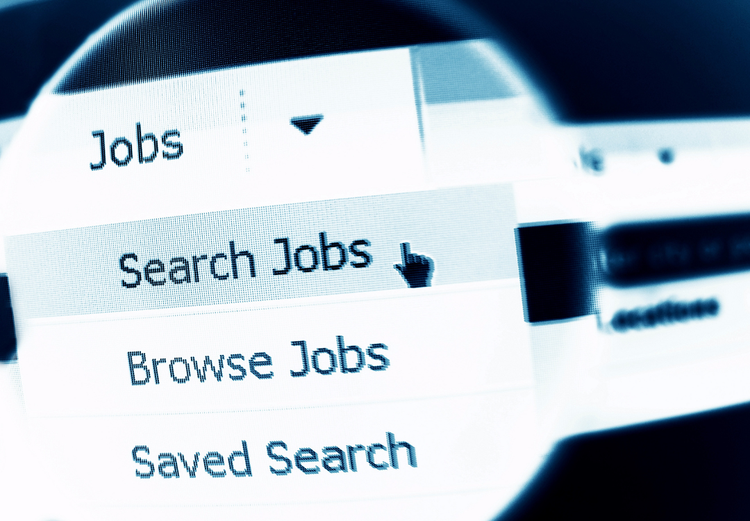 Person using a smartphone with email icons overlaying, near an open laptop in a cafe.