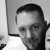 Black and white close-up of a fair-skinned man with short dark hair looking at the camera.