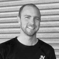 Man in black shirt smiling in front of a horizontal, textured background.
