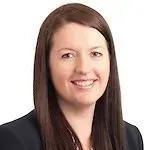 Woman with brown hair smiling in a suit, likely a professional headshot.