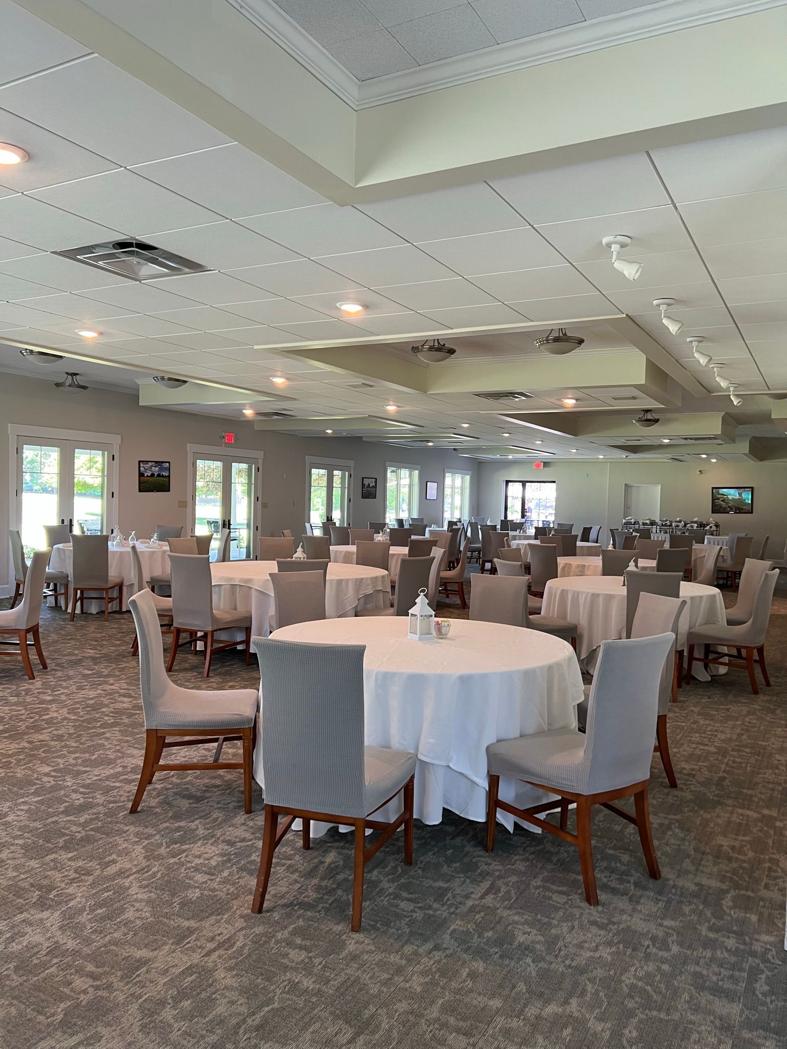A large room with tables and chairs set up for a wedding reception.