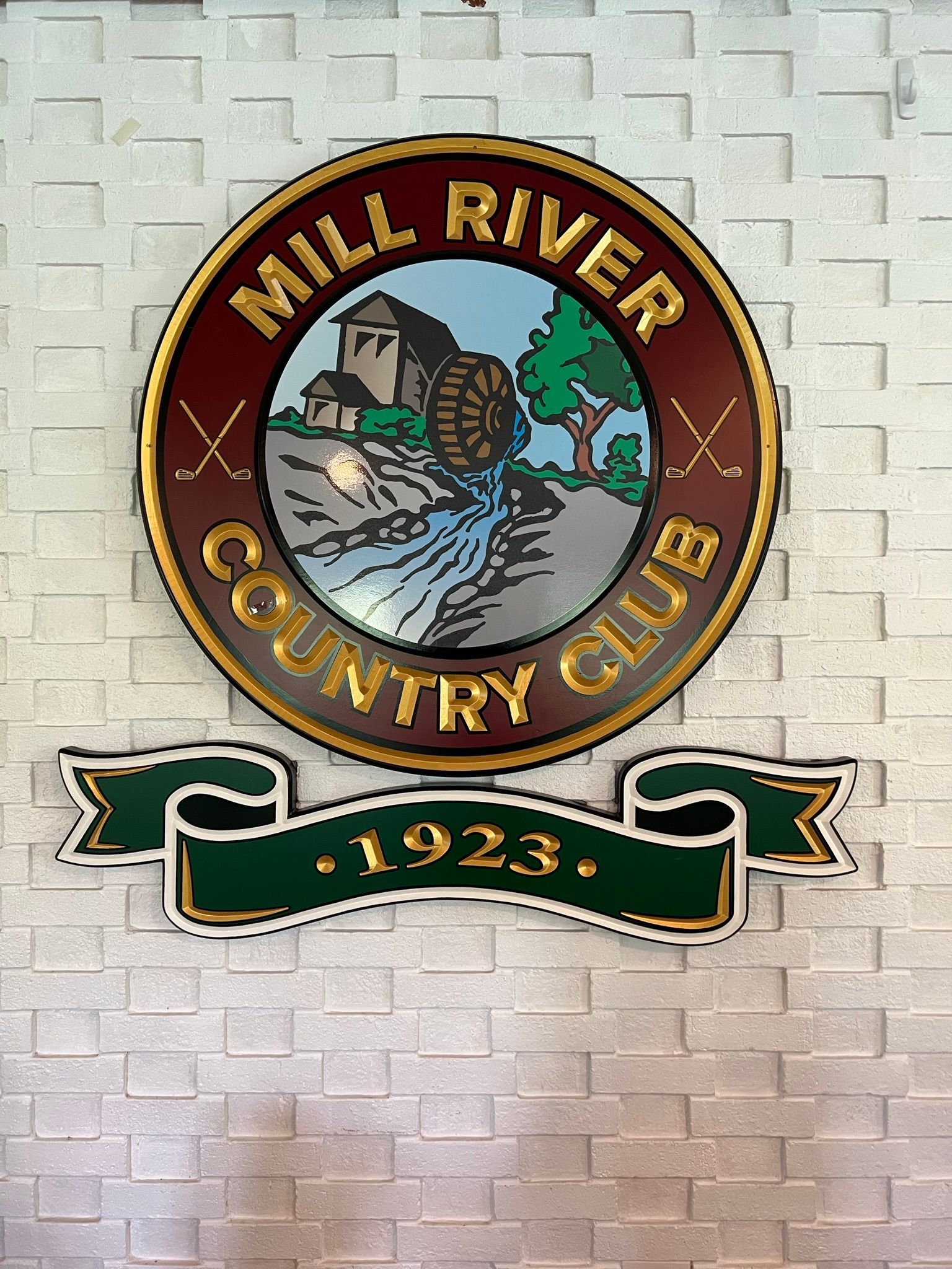 The mill river country club logo is on a white brick wall