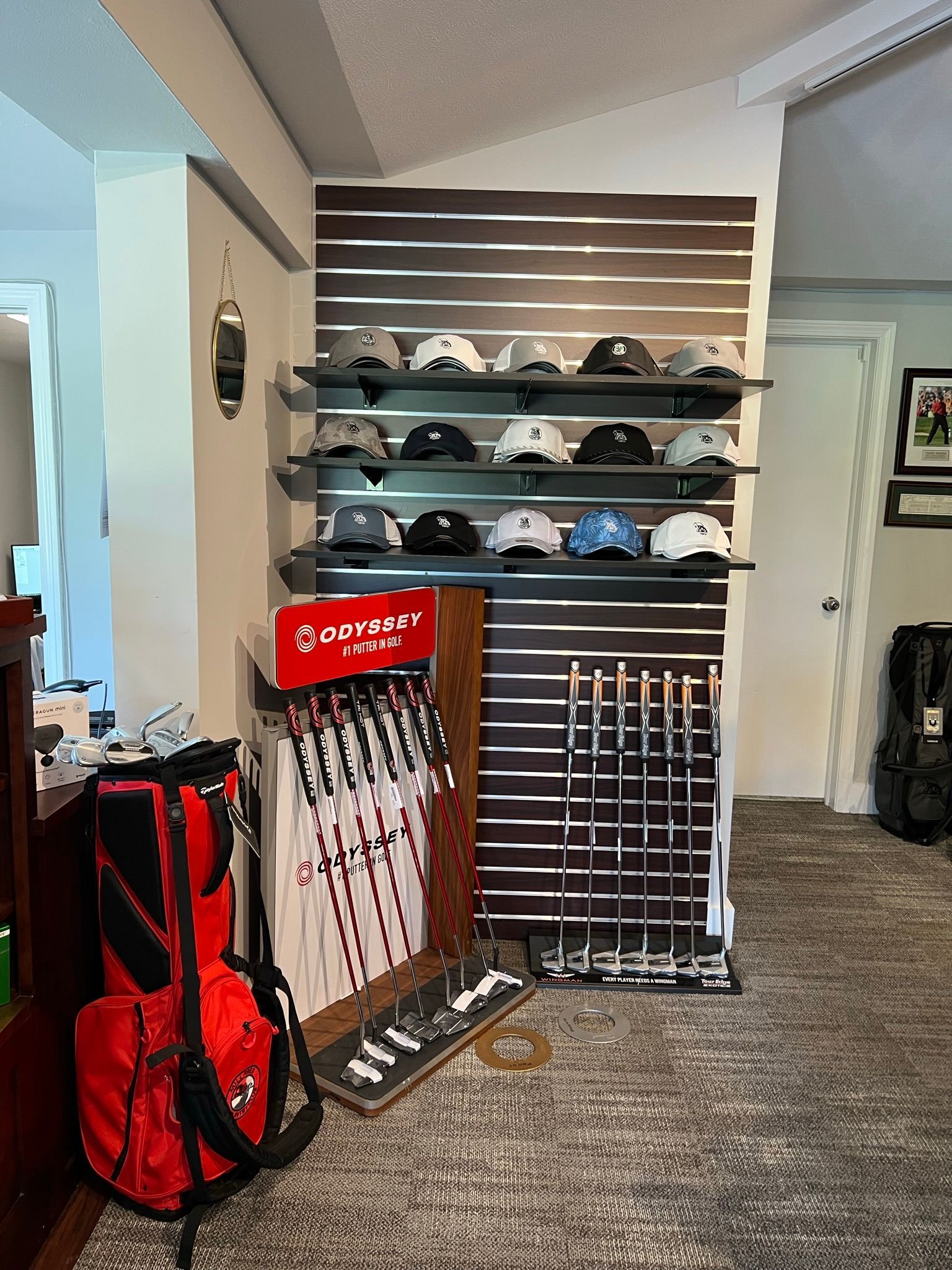 A room with a display of golf clubs and a red bag