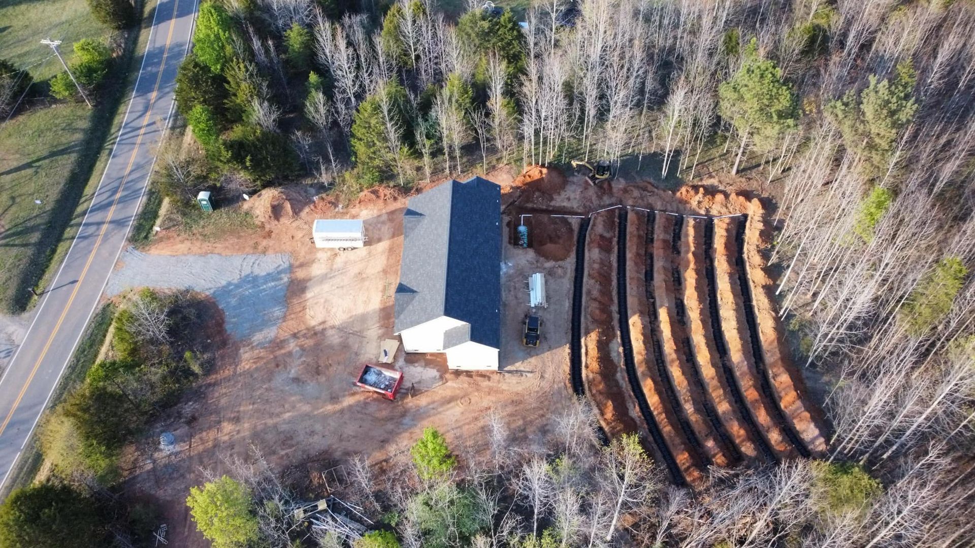 Aerial view of a building under construction with long, curved trenches in the surrounding dirt.