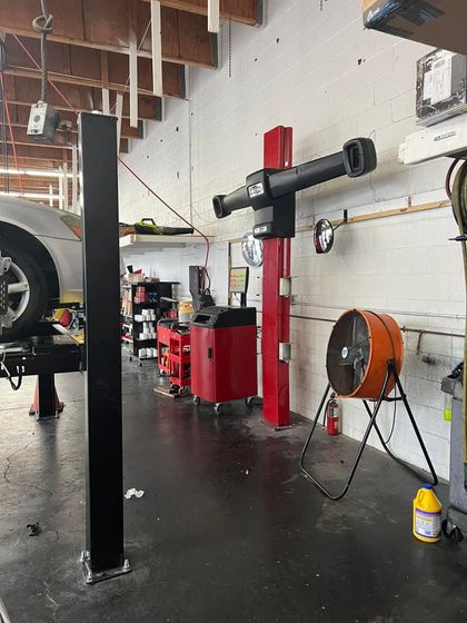 Auto repair shop interior with a red lift, tools, and a car on the left | Miller Auto Repair