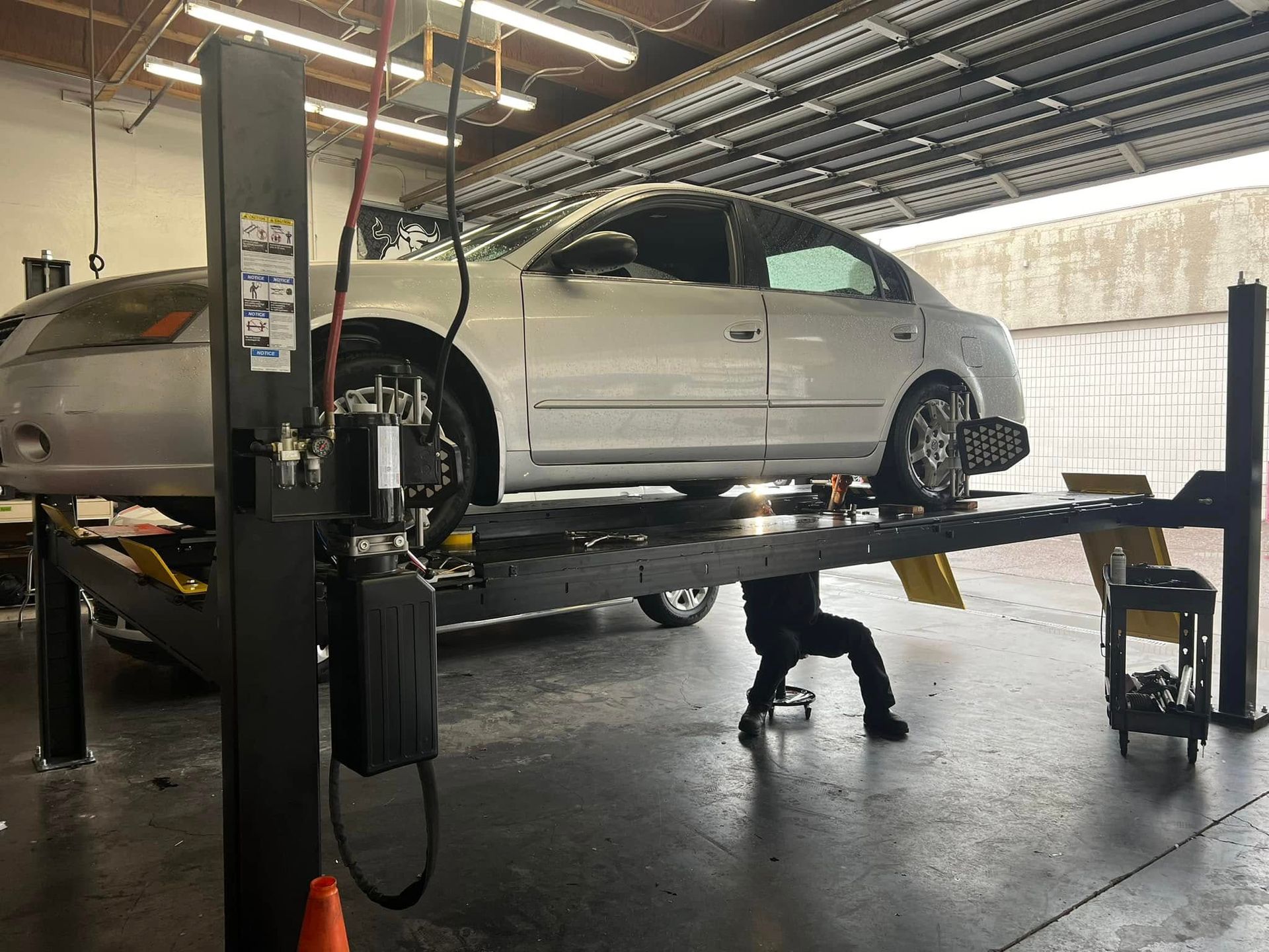 Silver sedan raised on a car lift in an auto repair shop | Miller Auto Repair Shop