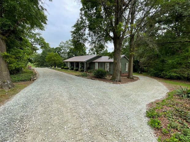 Skid steer loader on gravel road in front of a white warehouse with 