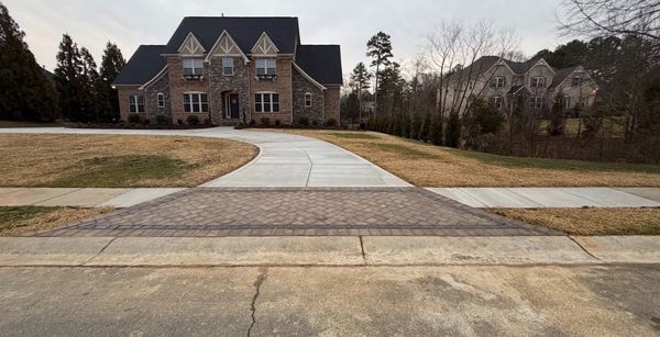 Rock and mulch landscaping in front of a building with a white fence, parked cars to the left, and trees.