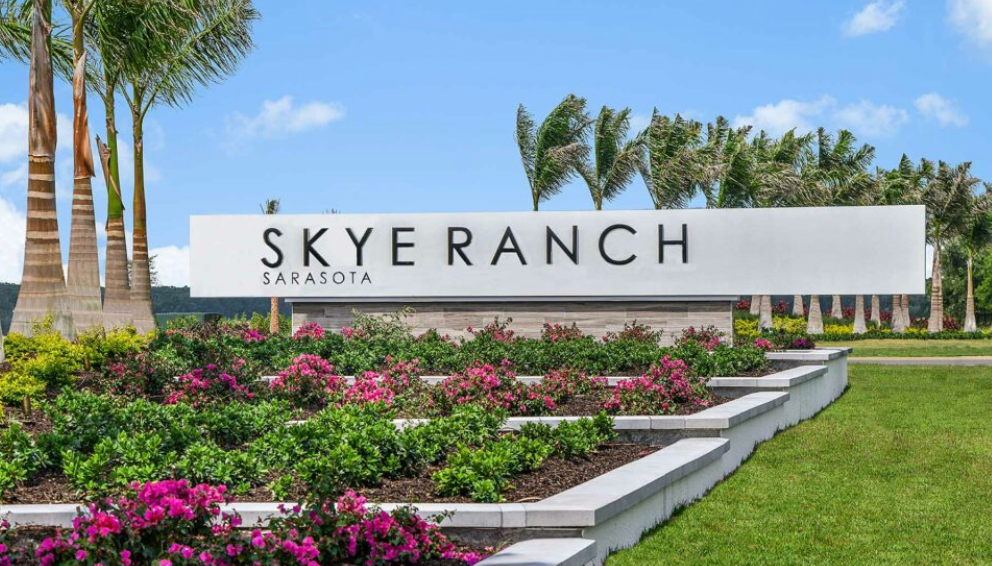 Skye Ranch Sarasota community surrounded by lush landscaping, palm trees, and colorful flowers. 