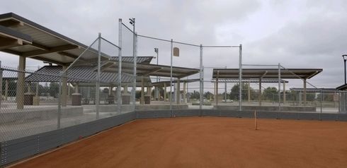 A baseball field with a fence and a stadium in the background