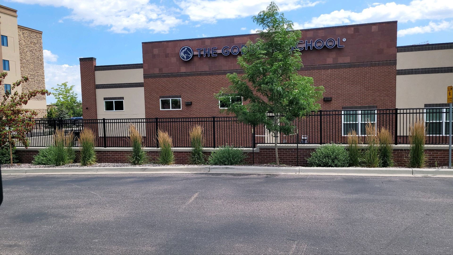 A large brick building with a fence built by Greater Western Fence and trees in front of it.