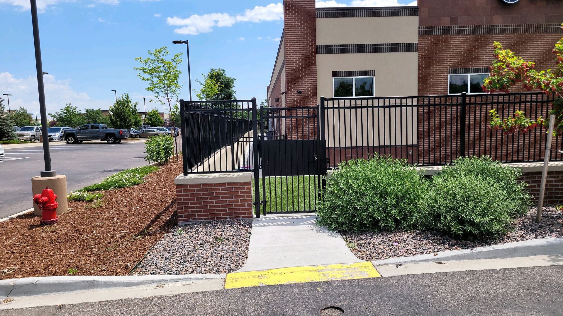A brick building with a black fence built by Greater Western Fence and a fire hydrant in front of it