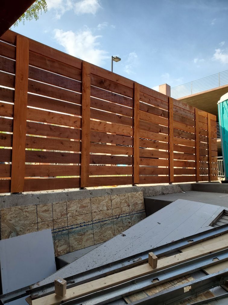A wooden fence surrounds a building under construction