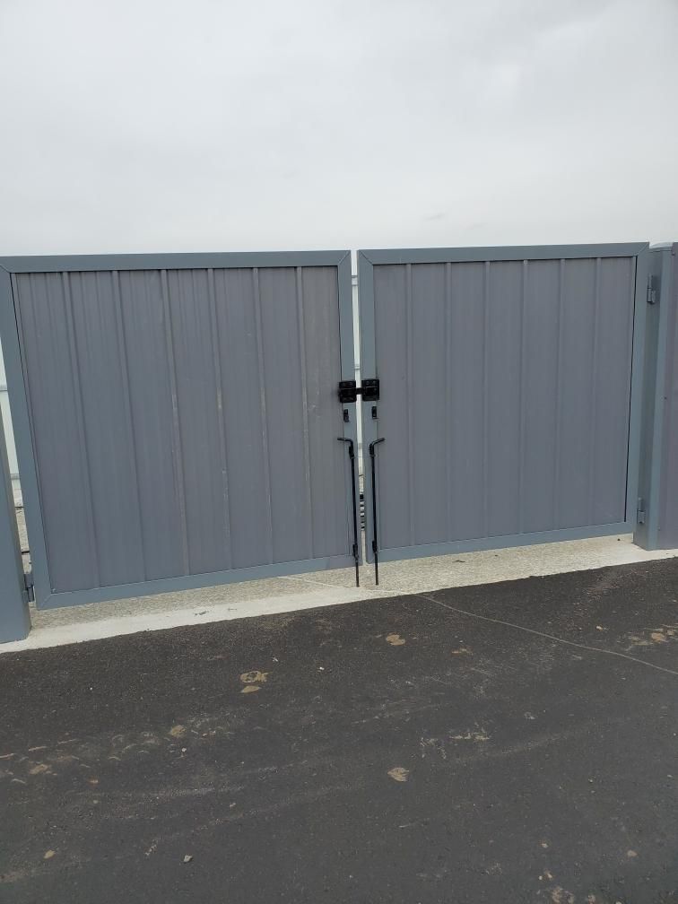 A gray gate is sitting on the side of a road.