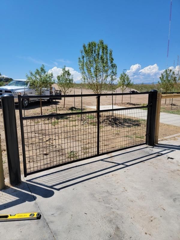 A fence with a truck parked behind it and trees in the background