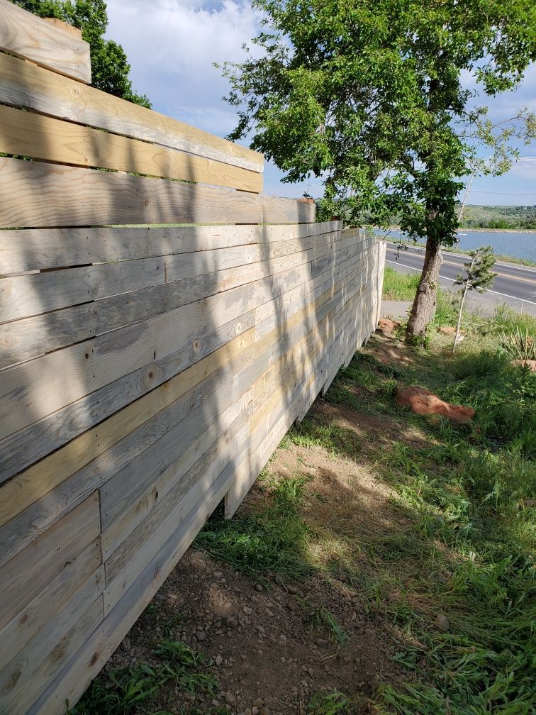 A wooden fence built by Greater Western Fence is sitting in the middle of a grassy field.