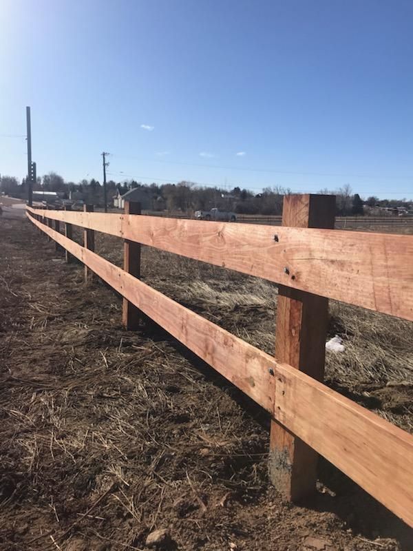 A wooden fence built by Greater Western Fence is sitting in the middle of a field.