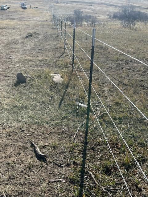 A barbed wire fence surrounds a dry grassy field.