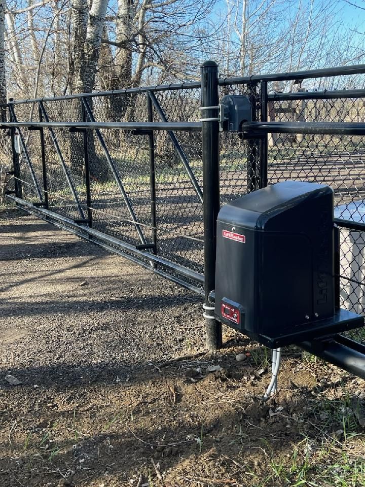 A sliding gate with a motor attached to it is sitting next to a chain link fence.