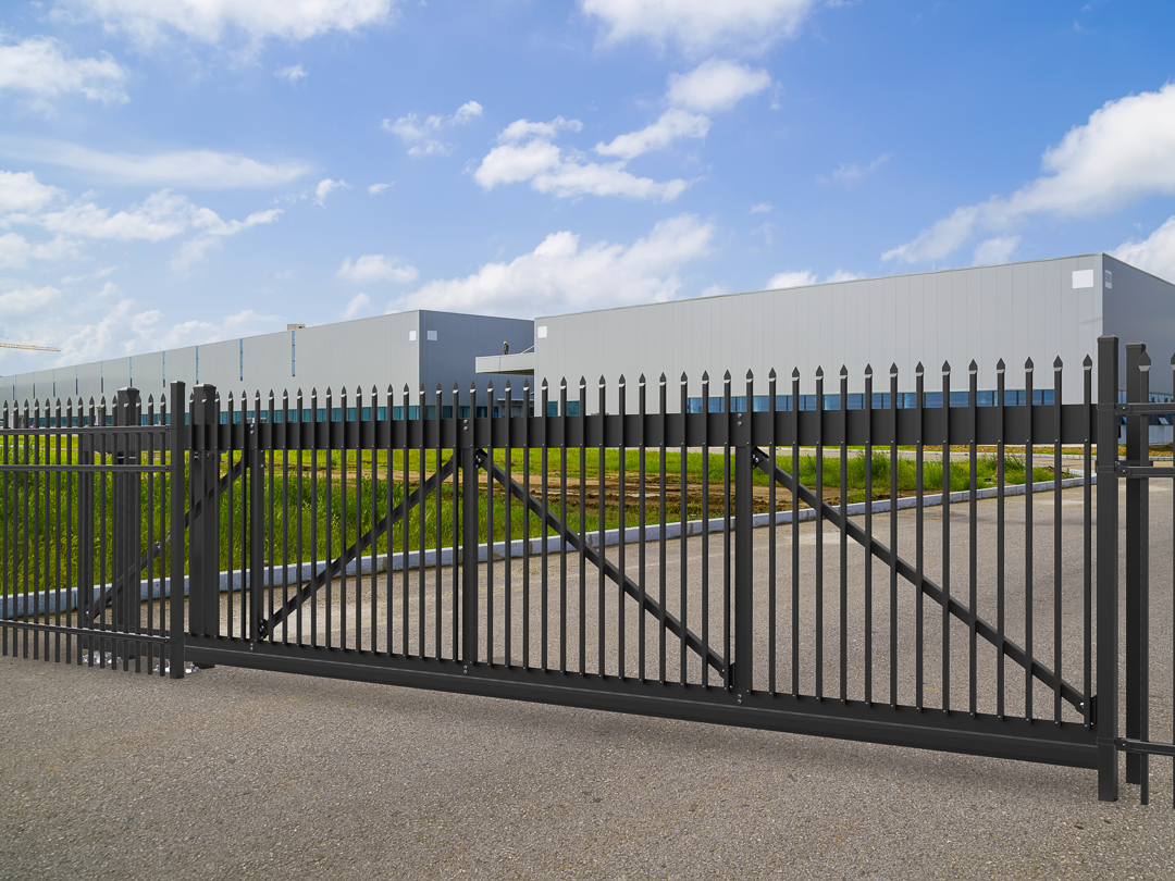 A large warehouse is behind a sliding gate built by Greater Western Fence.