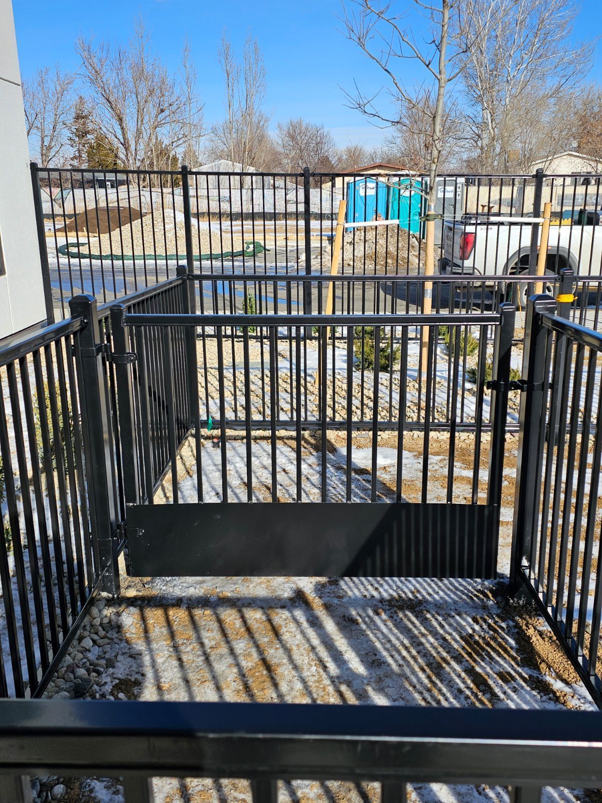 A black fence built by Greater Western Fence with a gate in the middle of a yard.