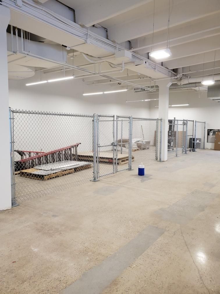 A large empty room with a chain link fence buit by Greater Western Fence surrounding it