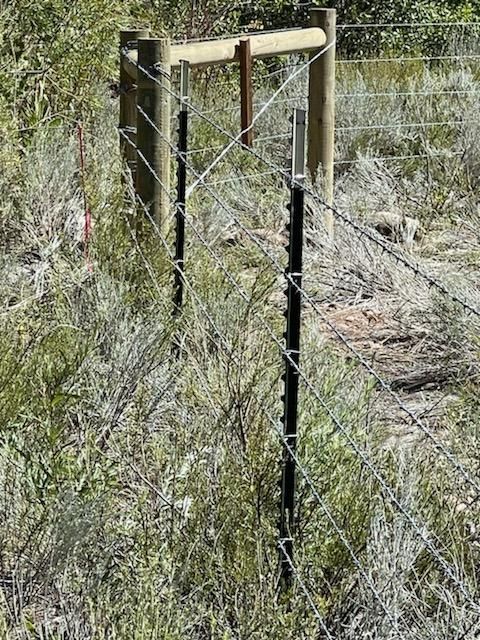 A barbed wire fence with a wooden post in the middle of a field.