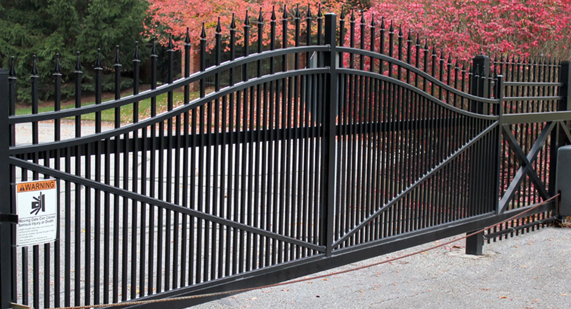 A black sliding gate built by Greater Western Fence is open to a driveway.