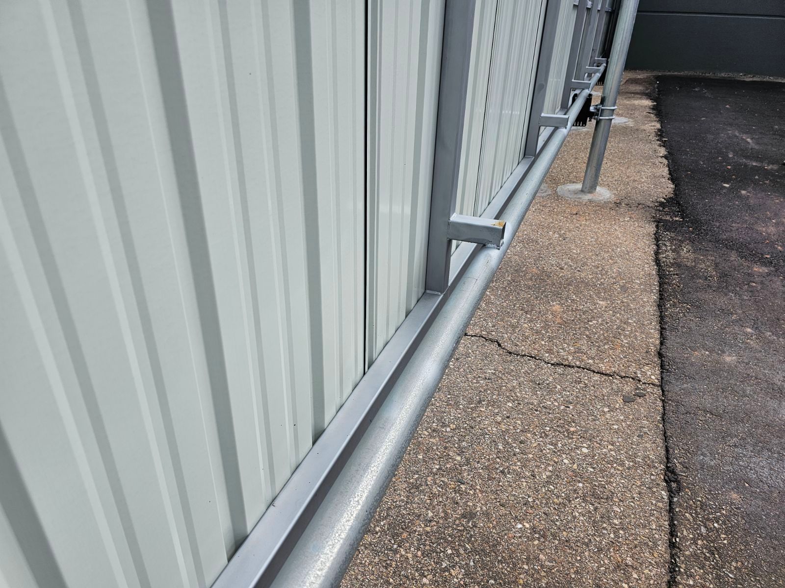 A close up of a metal fence buit by Greater Western Fence on a sidewalk next to a building.